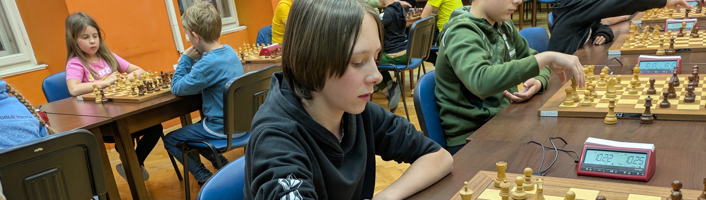 Igralci za šahovnicami s šahovskimi urami na turnirju
